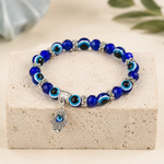 Rudvya Evil Eye Hamsa Bracelet with blue evil eye beads silver spacers and hamsa charm on stone display
